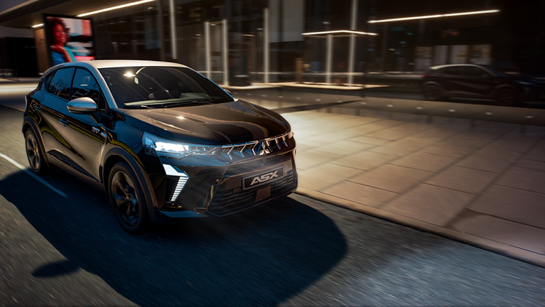 Mitsubishi ASX Black bei Nacht auf beleuchteter Stadtstraße mit eingeschalteten LED-Scheinwerfern